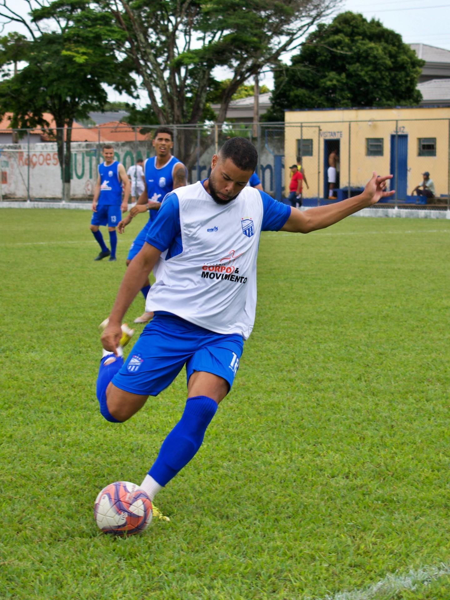 Soccer player celebrating a goal with arms raised, ball visible in the net behind him